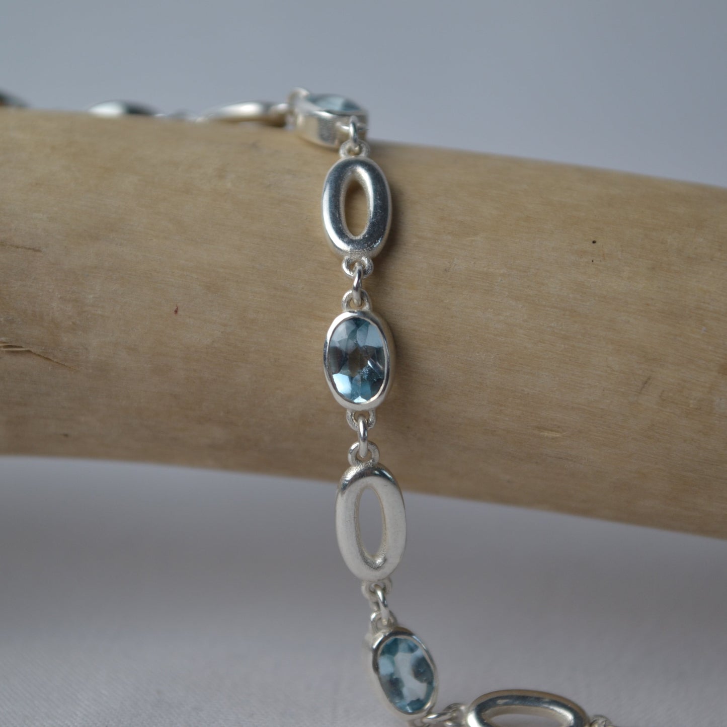 Silver bracelet with blue gemstones on a wooden surface