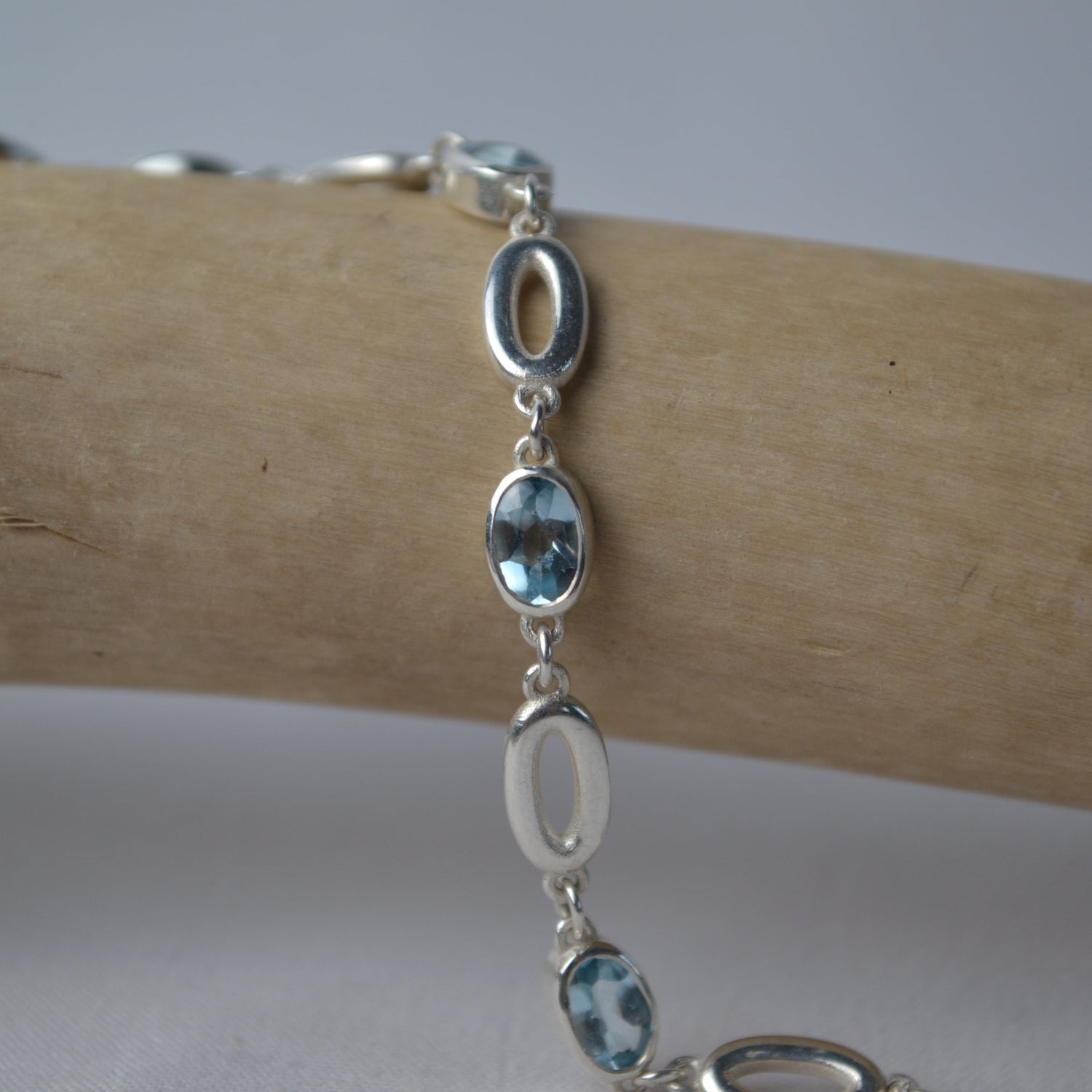 Silver bracelet with blue gemstones on a wooden surface