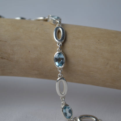 Silver bracelet with blue gemstones on a wooden surface