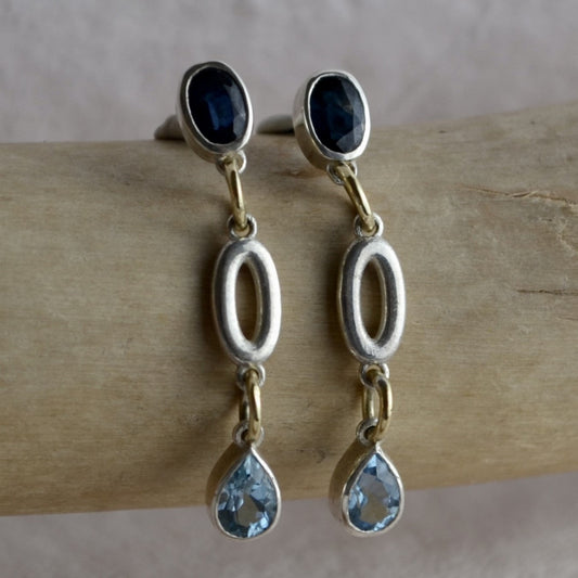 Pair of earrings with blue gemstones on a wooden surface