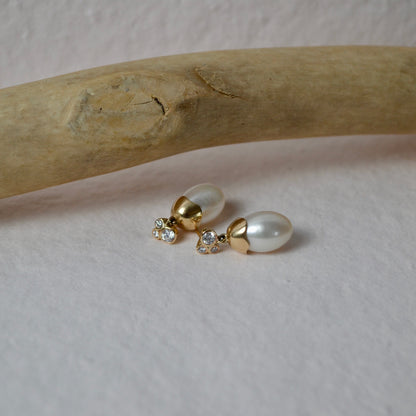 Pair of pearl earrings on a wooden stick with a neutral background