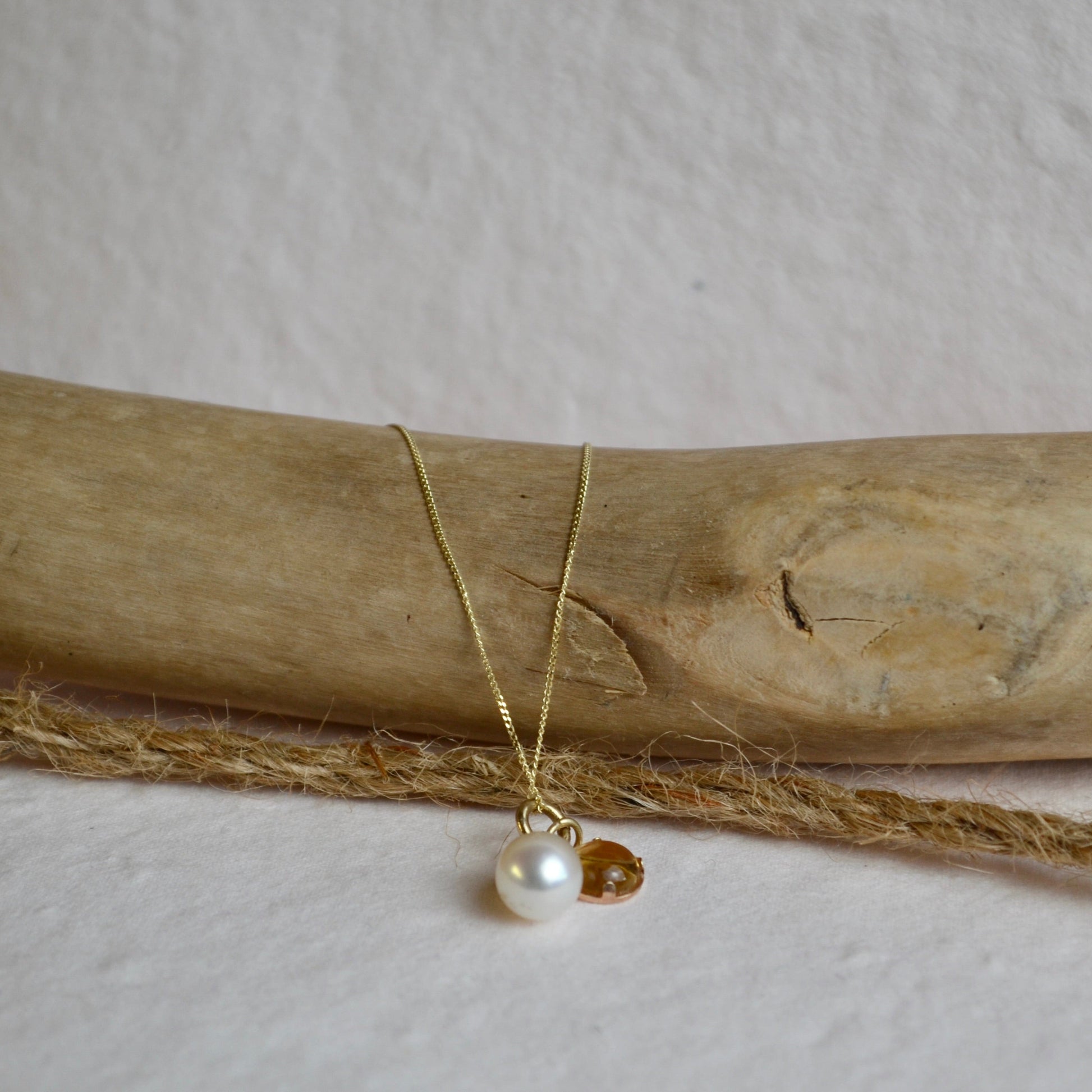 Gold necklace with a pearl pendant on a wooden stick