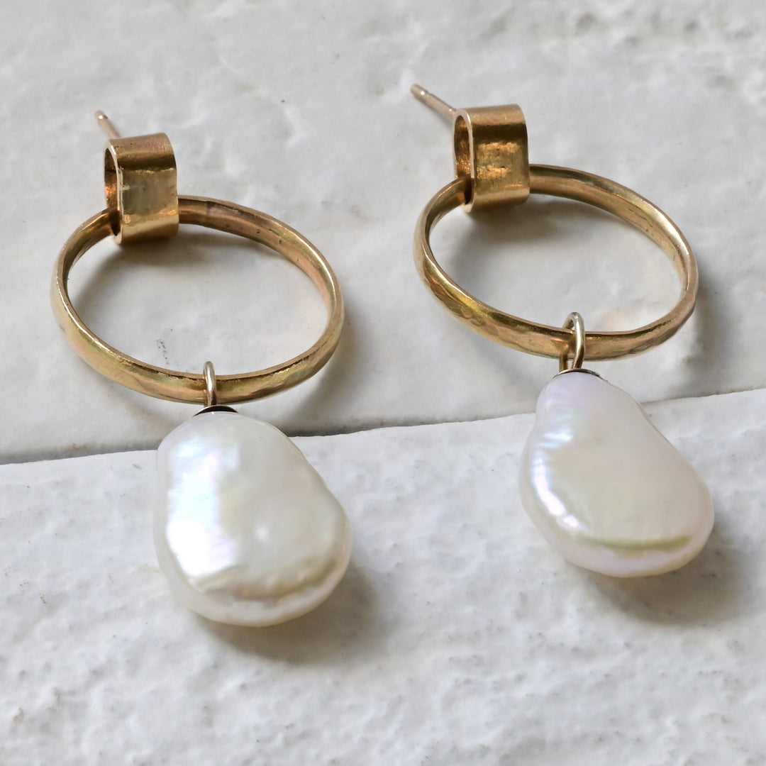 A pair of 9ct yellow gold hoop earrings with two pear-shaped white freshwater pearls attached to the hoops, displayed against a light background.