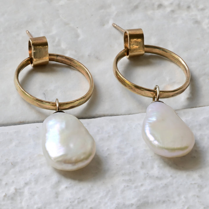 A pair of 9ct yellow gold hoop earrings with two pear-shaped white freshwater pearls attached to the hoops, displayed against a light background.