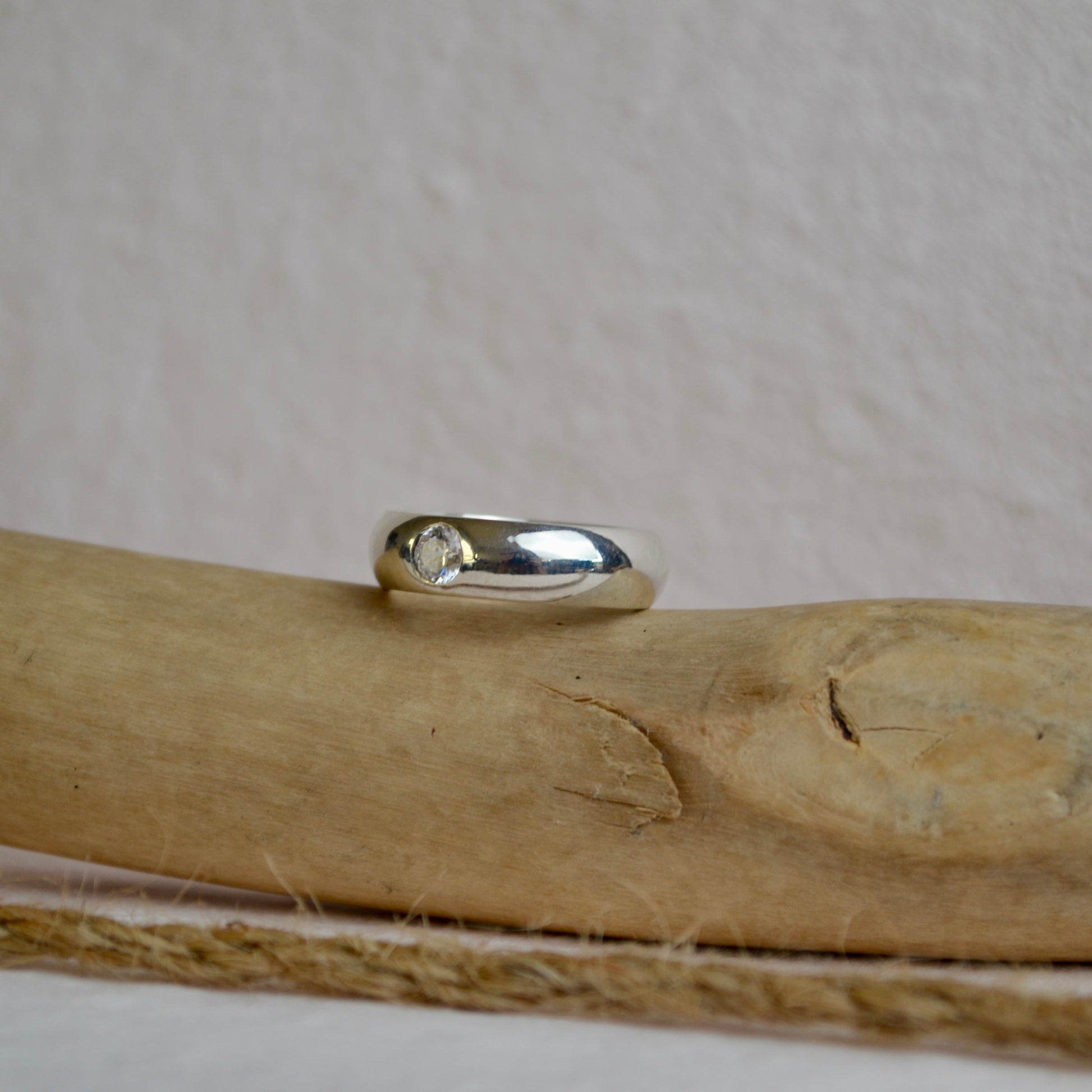 Silver ring on a wooden surface with a beige background