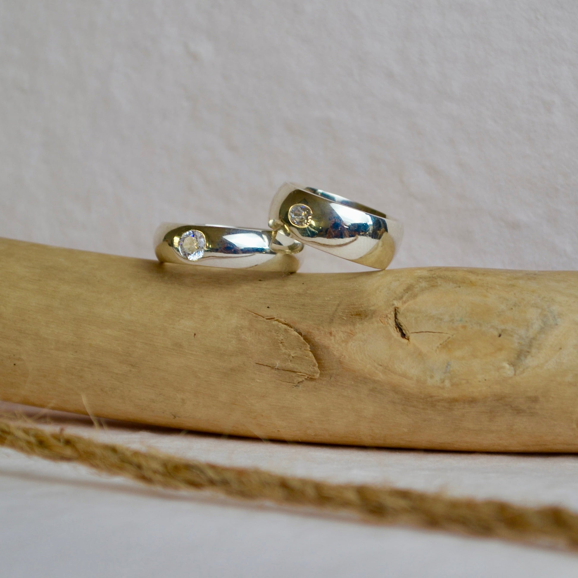 Silver ring with small stones on a wooden stick against a white background