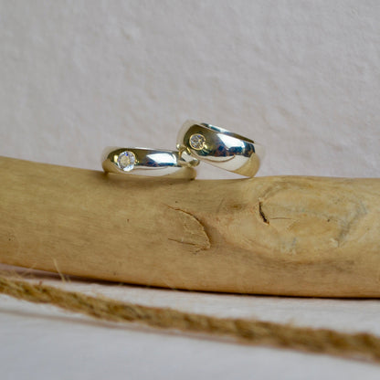 Silver ring with small stones on a wooden stick against a white background