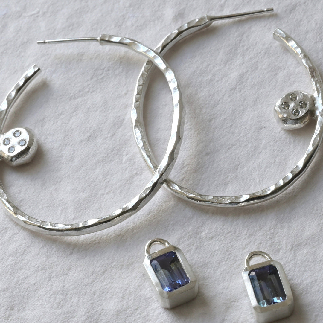 A pair of tanzanite and sterling silver hoops with diamond photographed on white. Handmade fine jewellery by Madeleine.