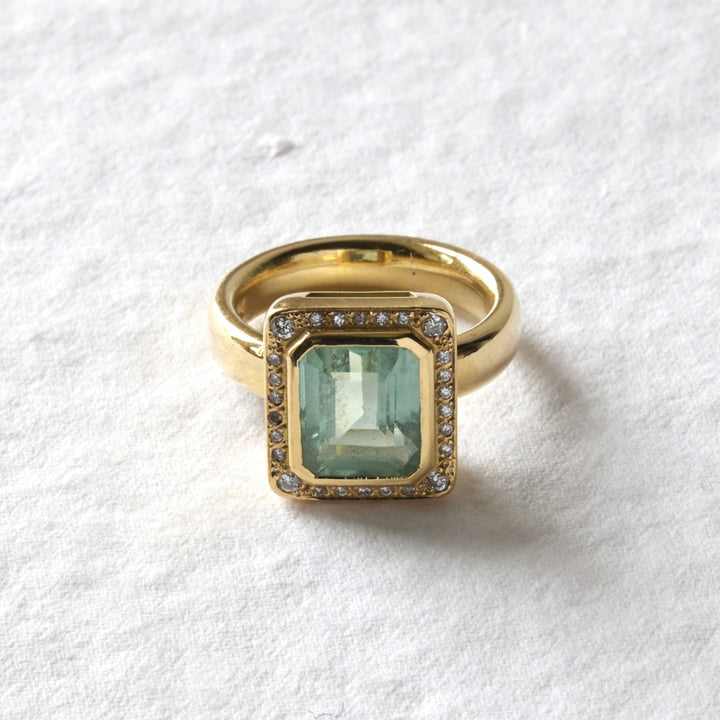 Gold ring with a green gemstone on a white background