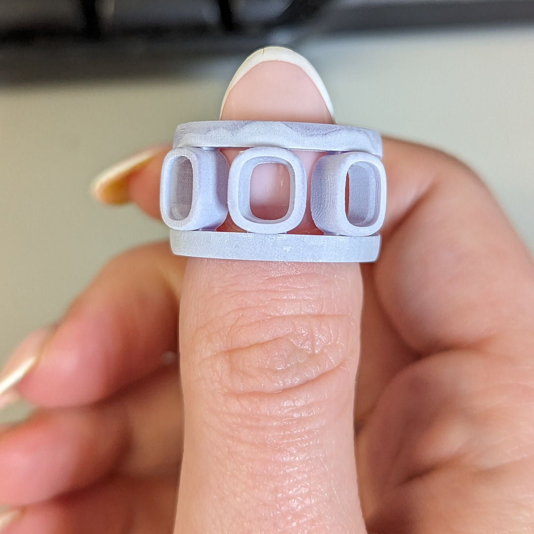 Hand holding a white ring with cut-out letters 'DOR' against a blurred keyboard background