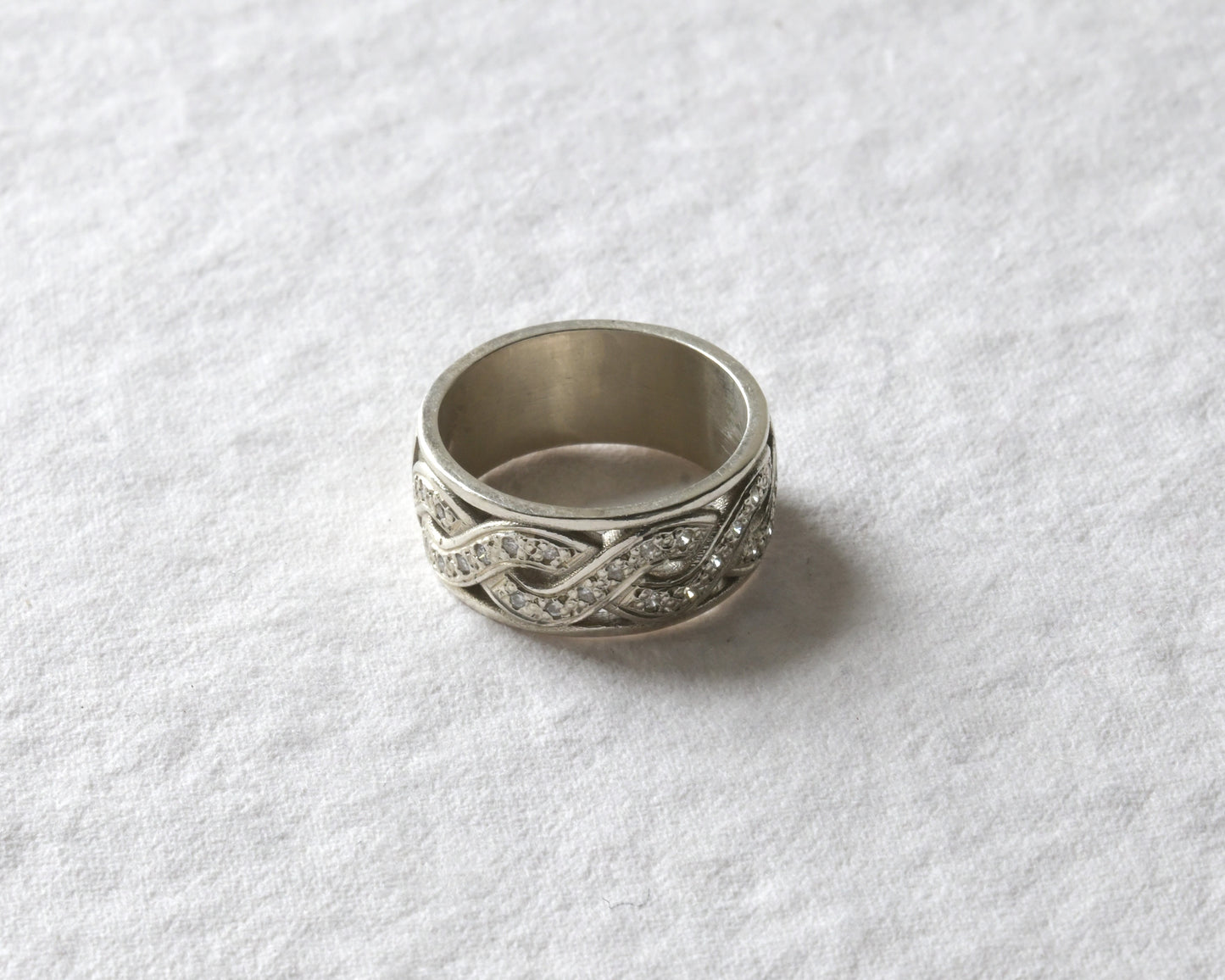 white gold celtic twist ring with diamonds pictured on white.