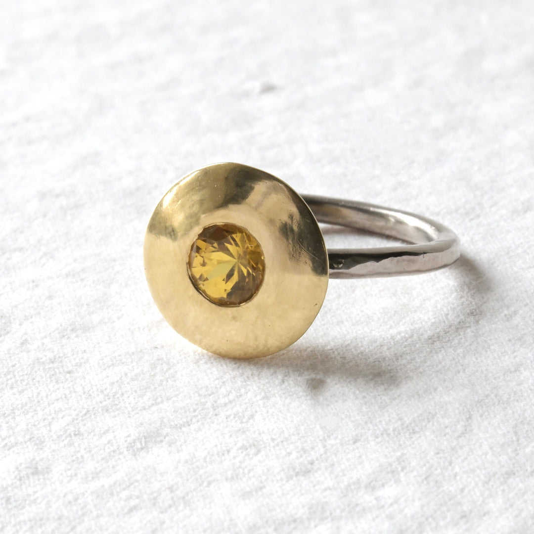 An 18ct gold engagement ring with a yellow sapphire at its centre, displayed on a white background.