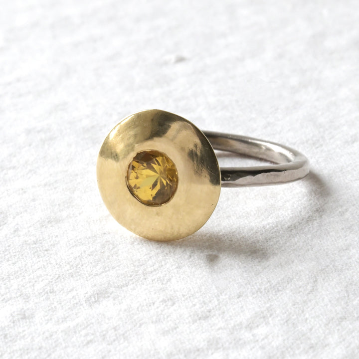 An 18ct gold engagement ring with a yellow sapphire at its centre, displayed on a white background.