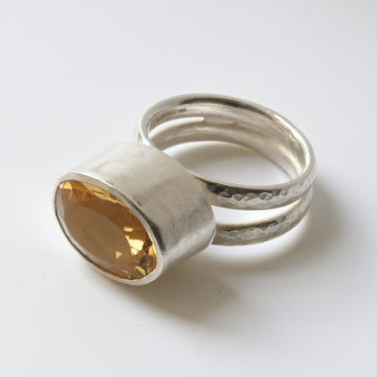 A sterling silver cocktail ring with a central faceted pale yellow citrine gemstone, surrounded by a double sterling silver band.
