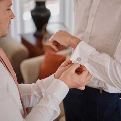 Best man putting on grooms personalised sterling silver cufflinks, handmade fine jewellery by Madeleine.