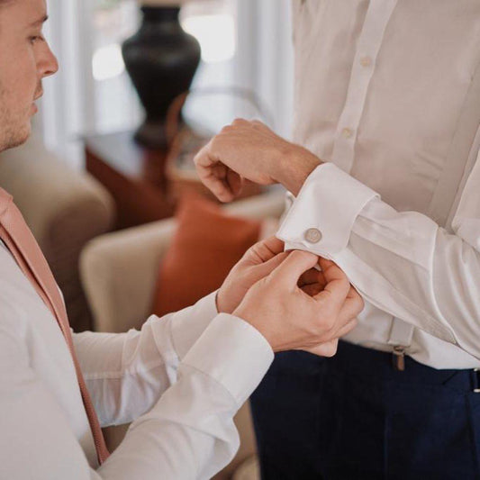Best man putting on grooms personalised sterling silver cufflinks, handmade fine jewellery by Madeleine.
