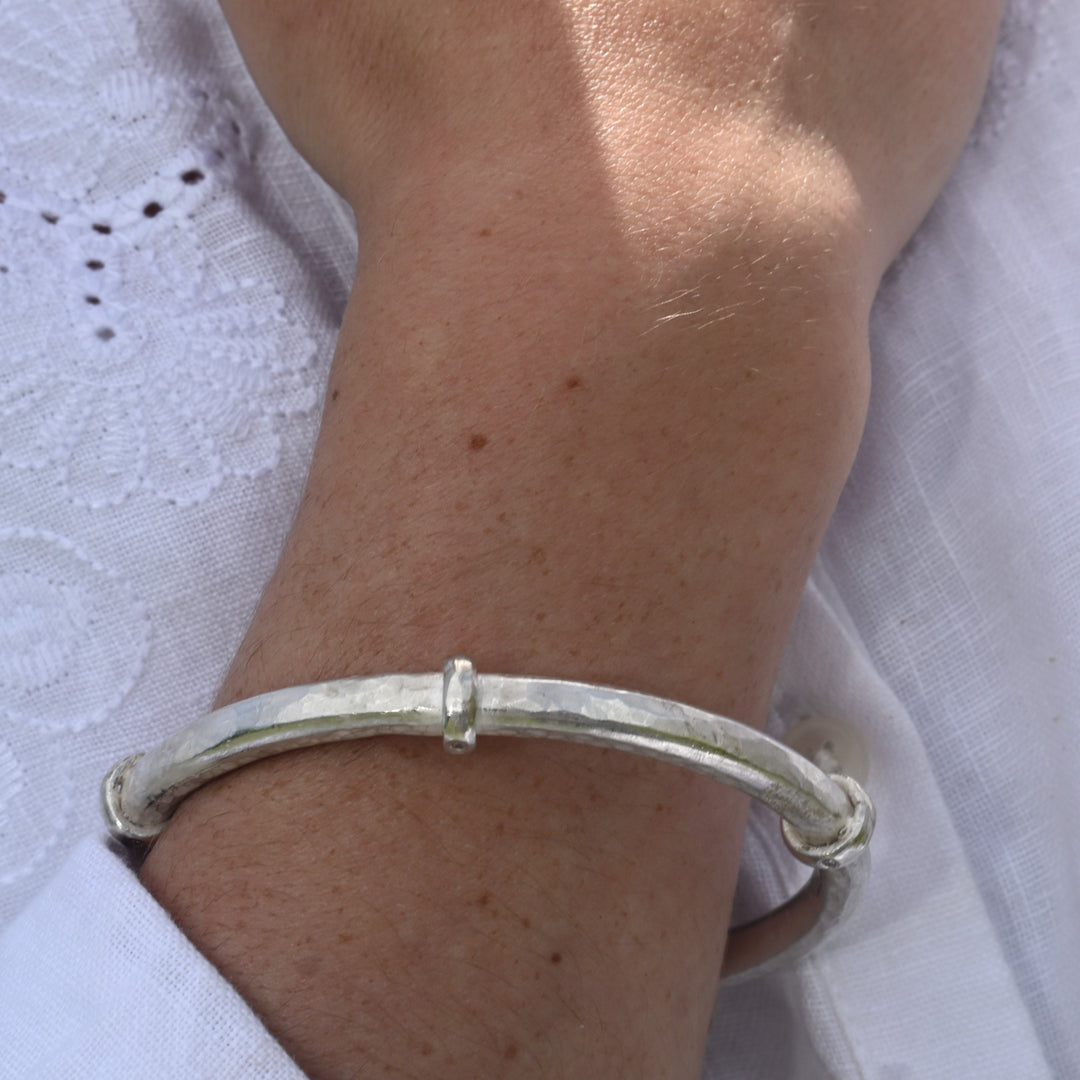 Hand wearing a silver bracelet on a white background