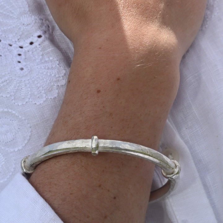 Hand wearing a silver bracelet on a white background