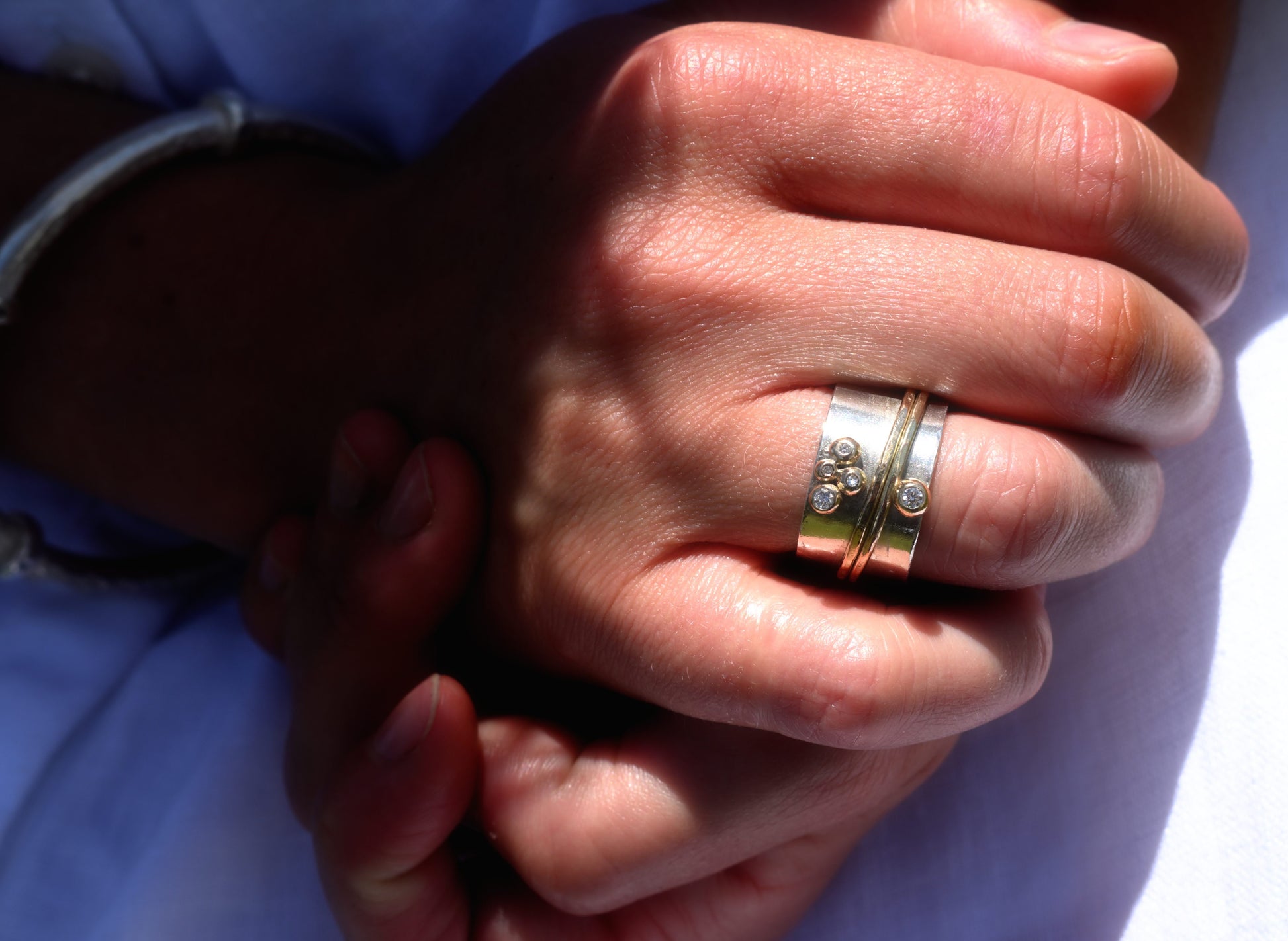 Madeleine wearing a white dress in the Cotswold's and the diamond, silver and gold sinning ring. Handmade fine jewellery by Madeleine.
