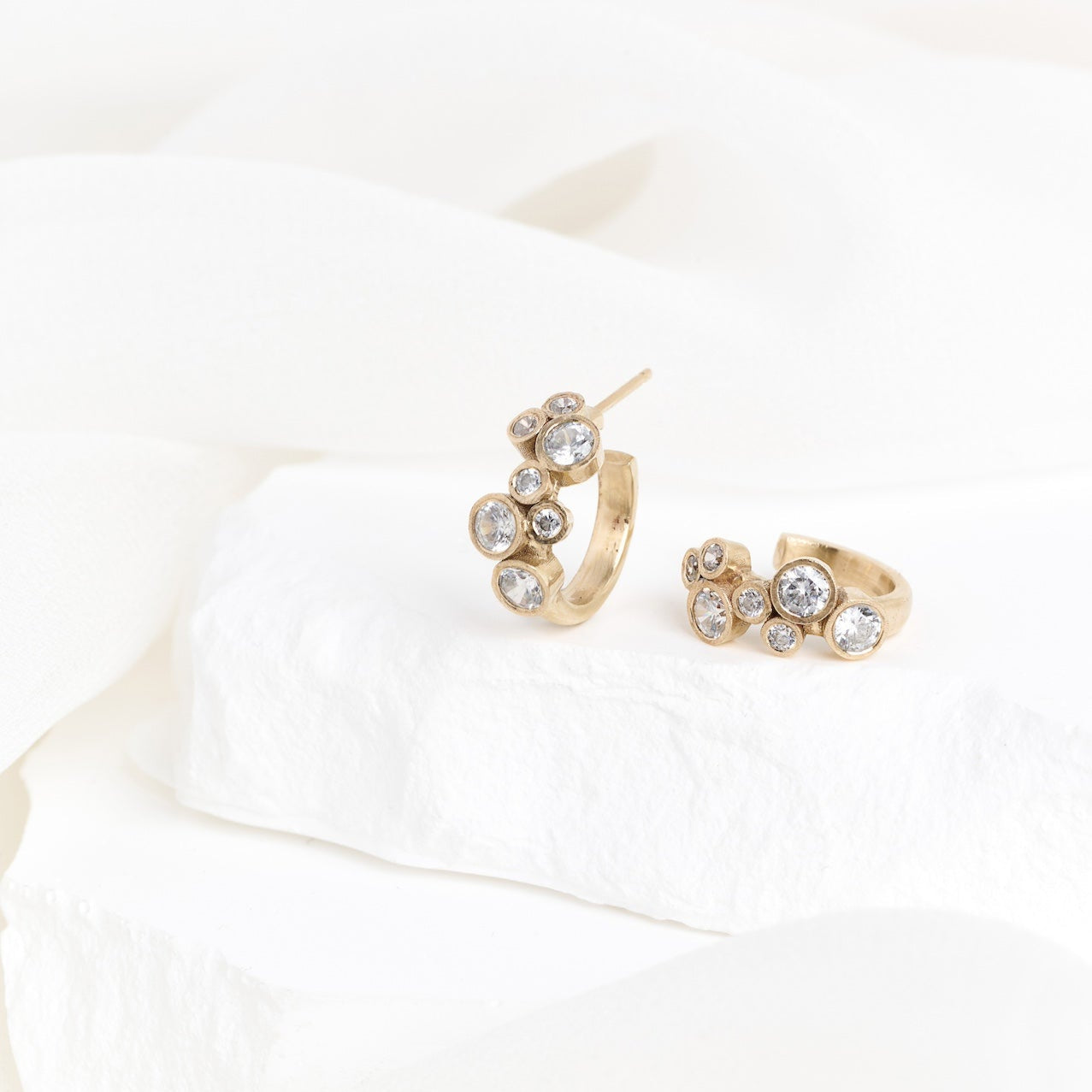A pair of yellow gold hoop earrings with scattered diamond accents, displayed against a white background.