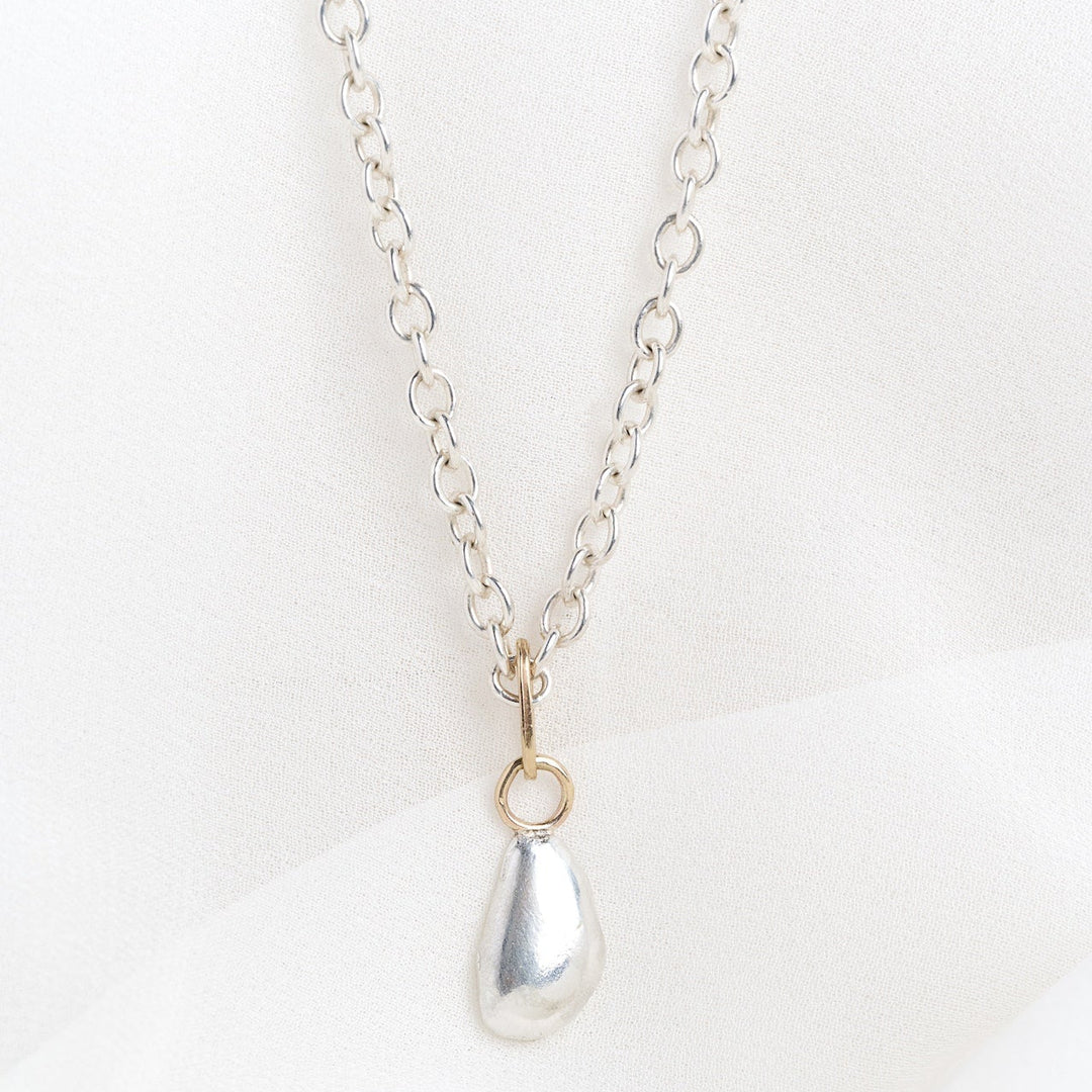 Silver necklace with a teardrop pendant on a white background