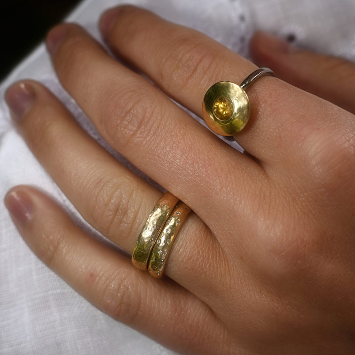 Madeleine wearing the diamond yellow gold wedding bad and the plain yellow gold wedding band stacked together on her left ring finger, pictured in the cotswolds.