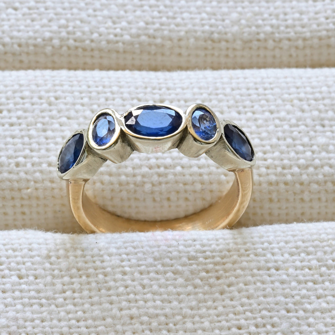 blue sapphire and gold engagement ring on white 