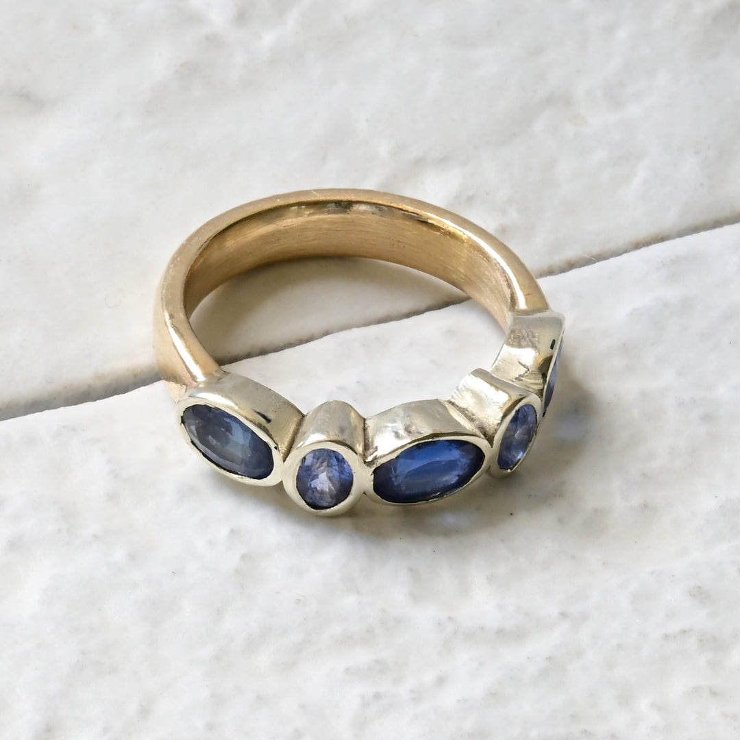 A gold engagement ring with alternate sapphires set in white gold on a yellow gold band.
