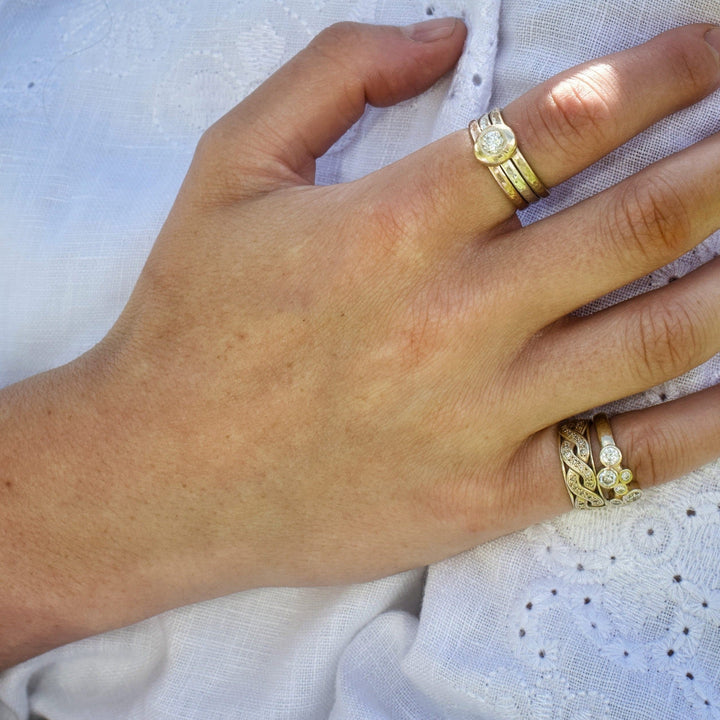 Madeleine wearing the yellow gold celtic diamond promise ring on her little finger, stacked with the scattered diamond eternity ring.